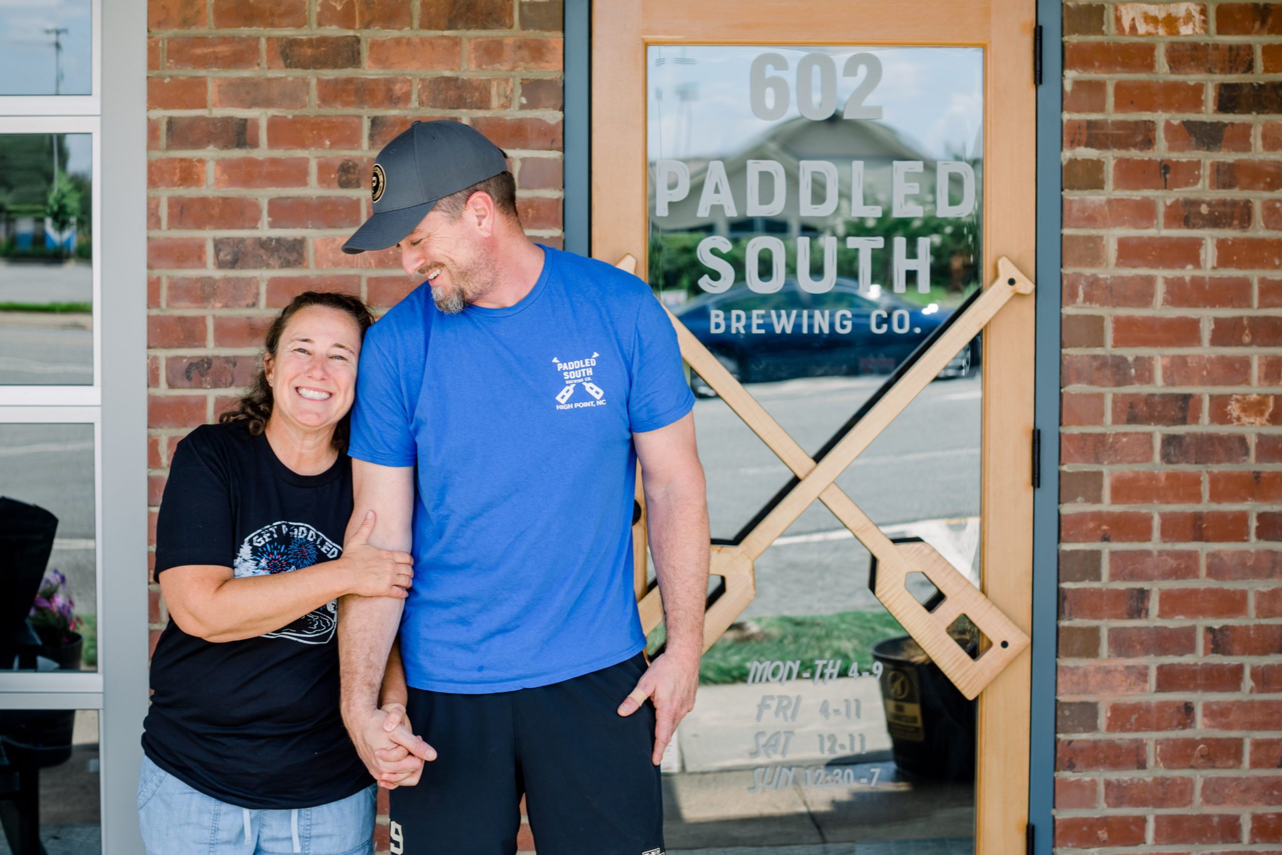 David and Amy Nissen, owners of Paddled South Brewing Co., stand hand-in-hand in front of the brewery.