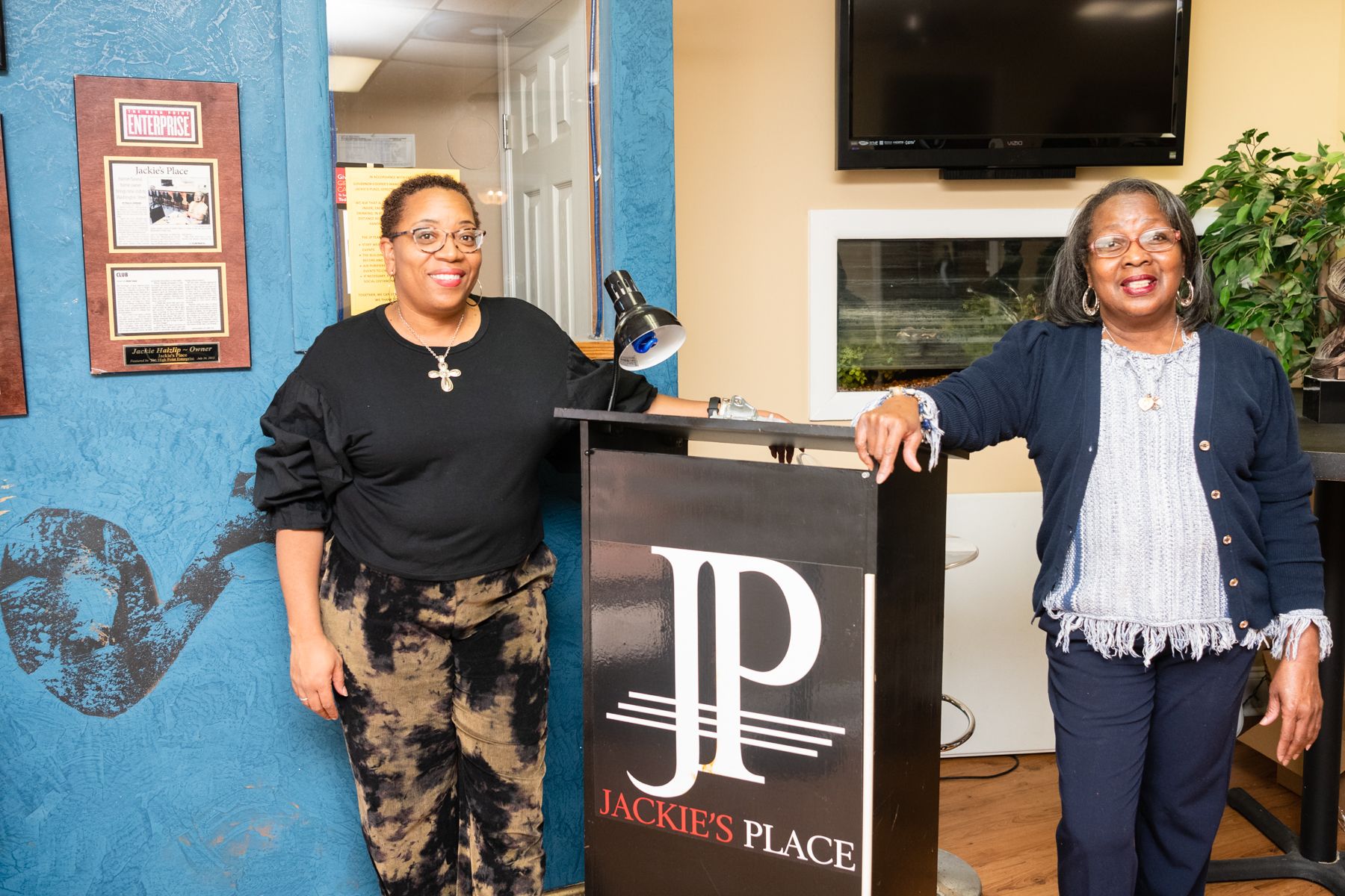 Rishaunda Moses and Raynetta Jackson stand in front of the welcome podium at Jackie's Place in High Point, NC.