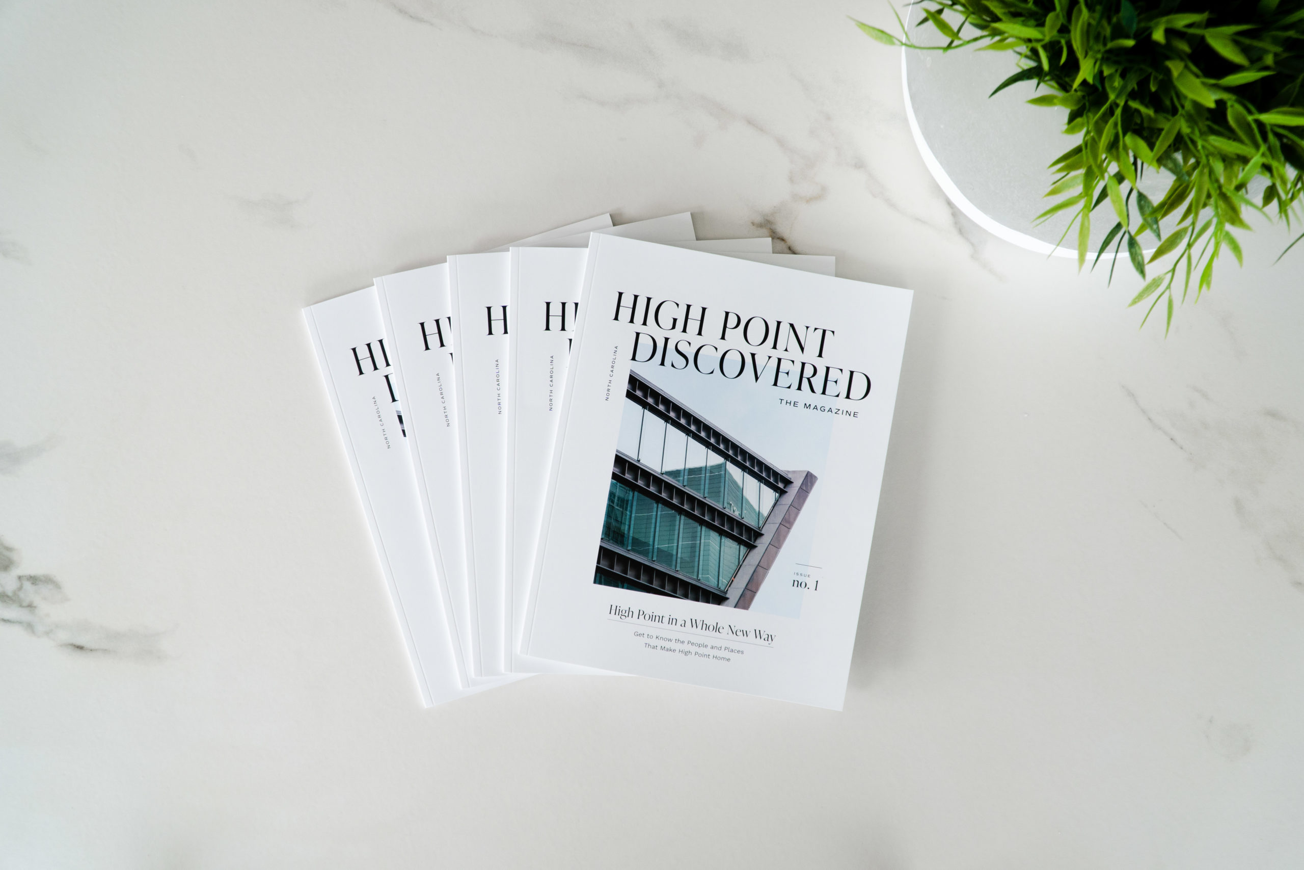 Several copies of High Point Discovered: The Magazine lay fanned on a table showcasing all that High Point, NC has to offer.