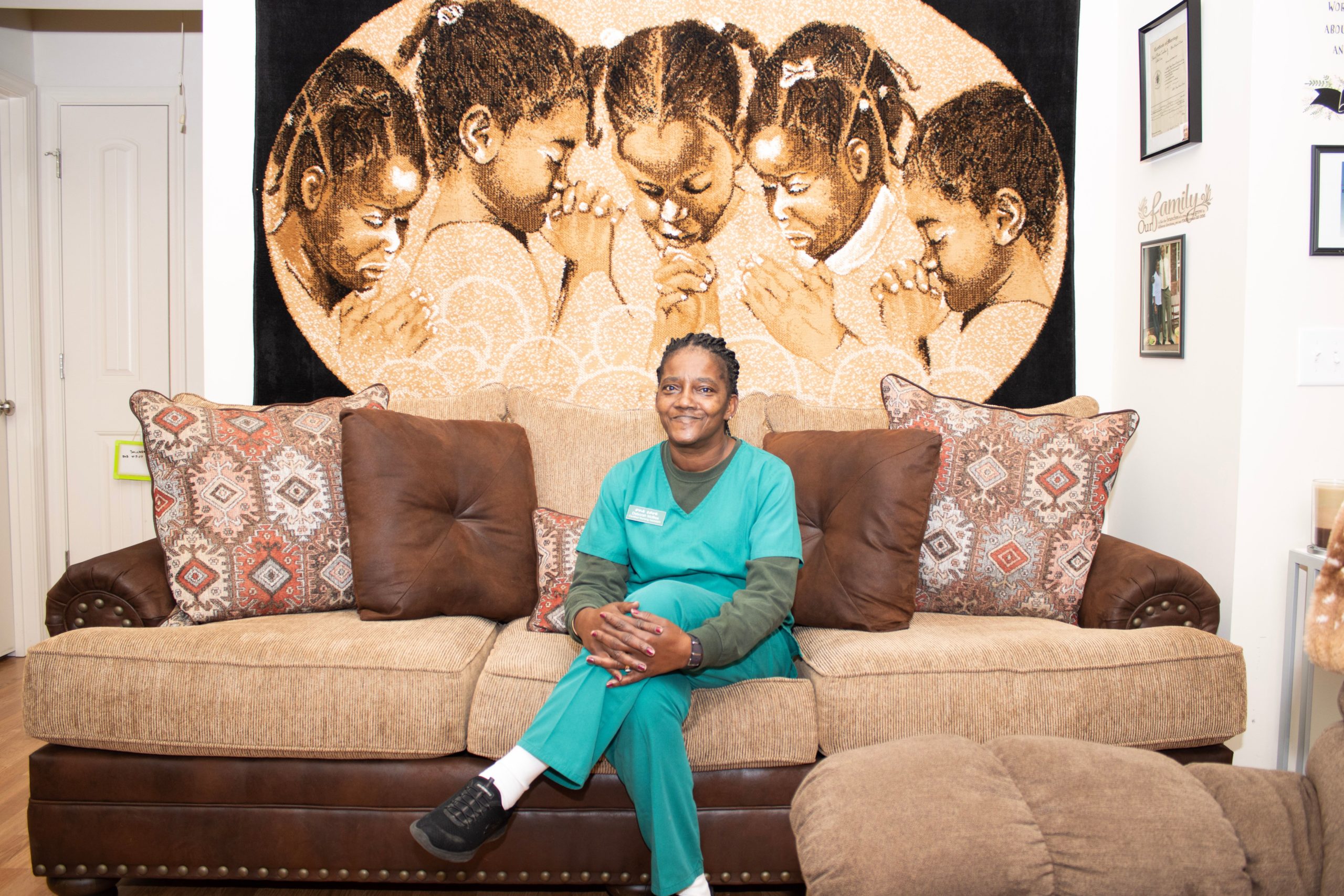 Ms McBee, a home health aide in High Point, NC sits on the couch in her new construction home, a home built through the Pinnacle Financial Partners affordable housing program.