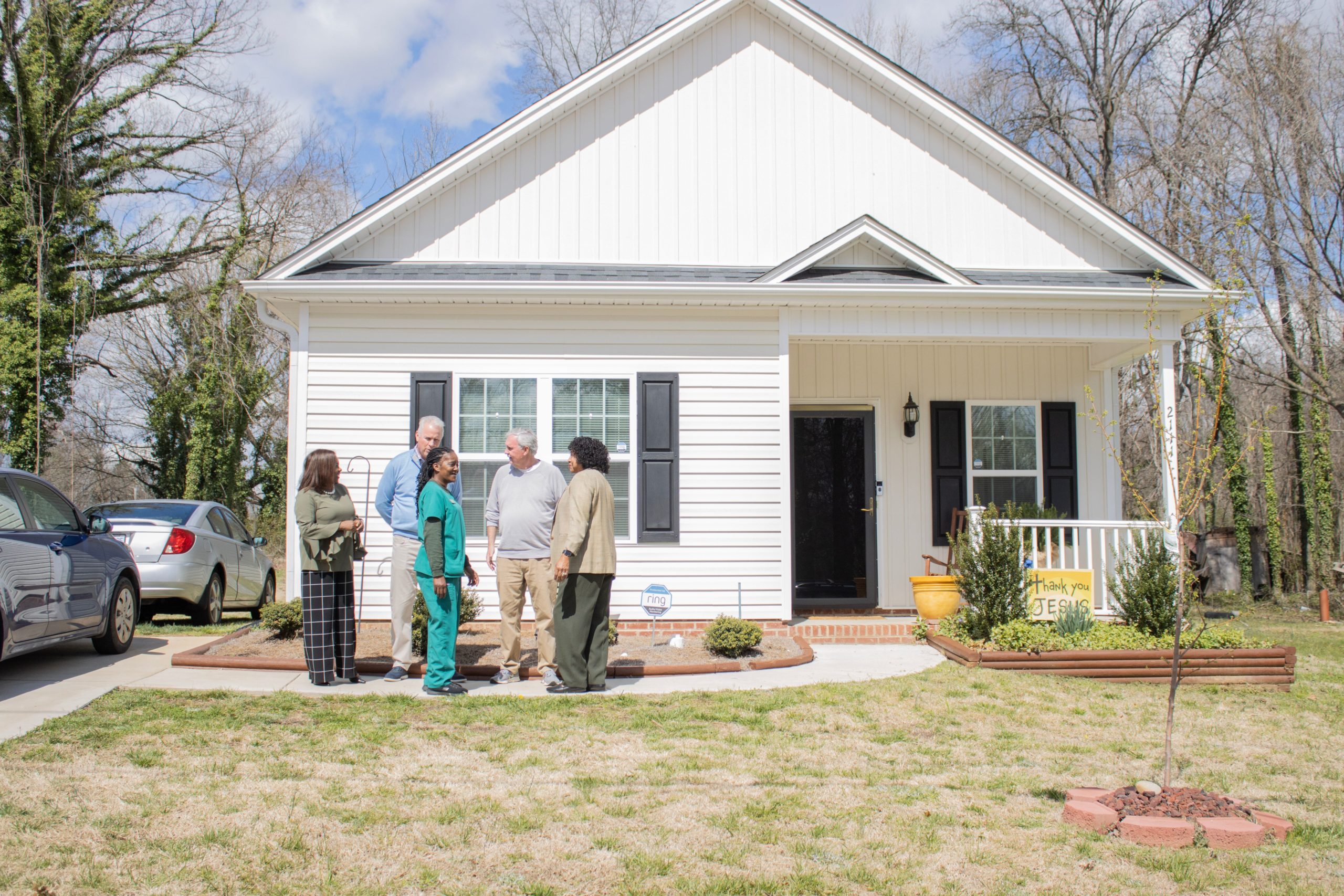 A group of people stand together in front of a new construction house in High Point, NC.