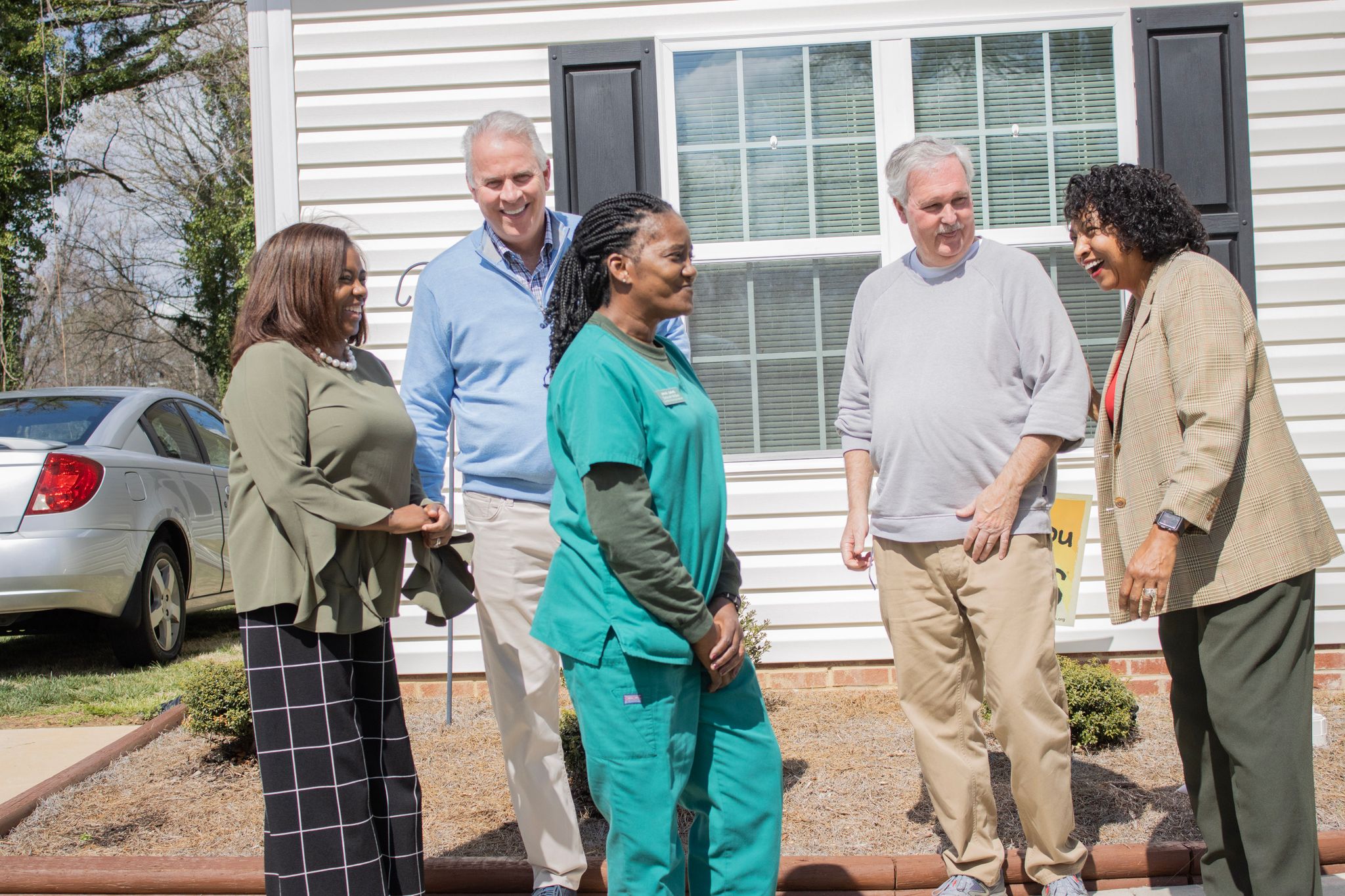 A group of professionals from Pinnacle Financial Partners stands in front of the homes as part of their Affordable Housing Program in High Point, NC.