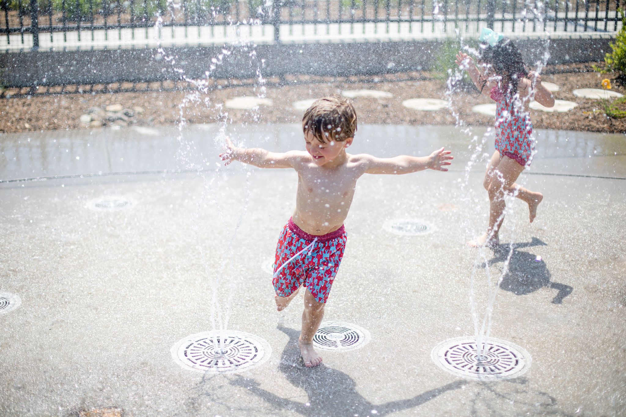 A little boy runs through a splash pad sprinkler in High Point, NC at Blessing Park.