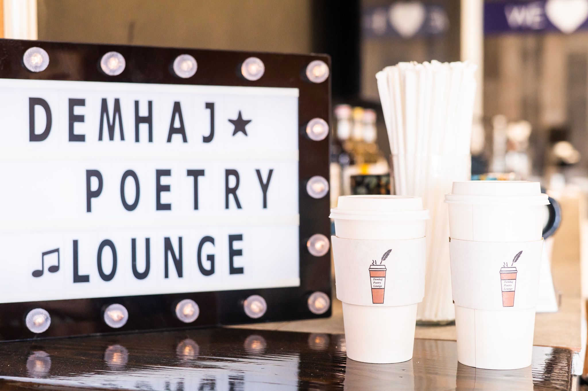 A sign that says Demhaj Poetry Lounge beside coffee cups in a coffee shop in High Point, NC.