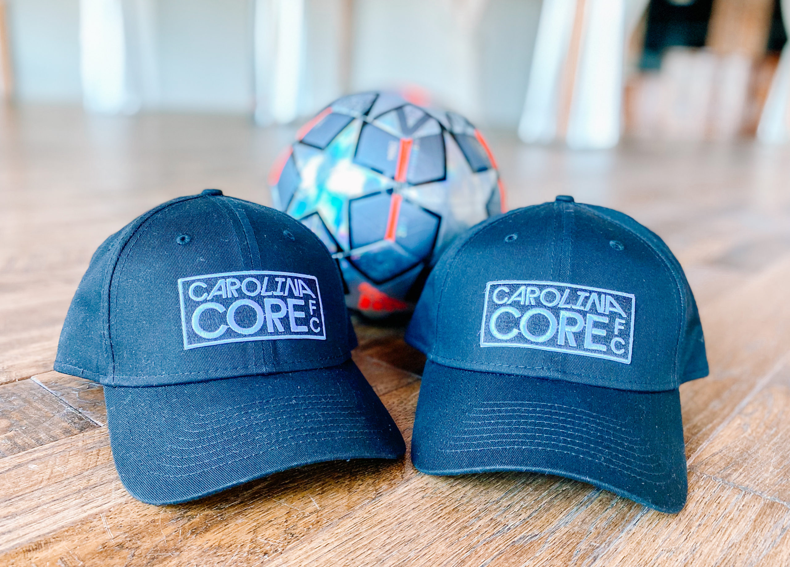 Two hats with the Carolina Core FC logo for the new MLS NEXT Pro soccer team in High Point, NC.
