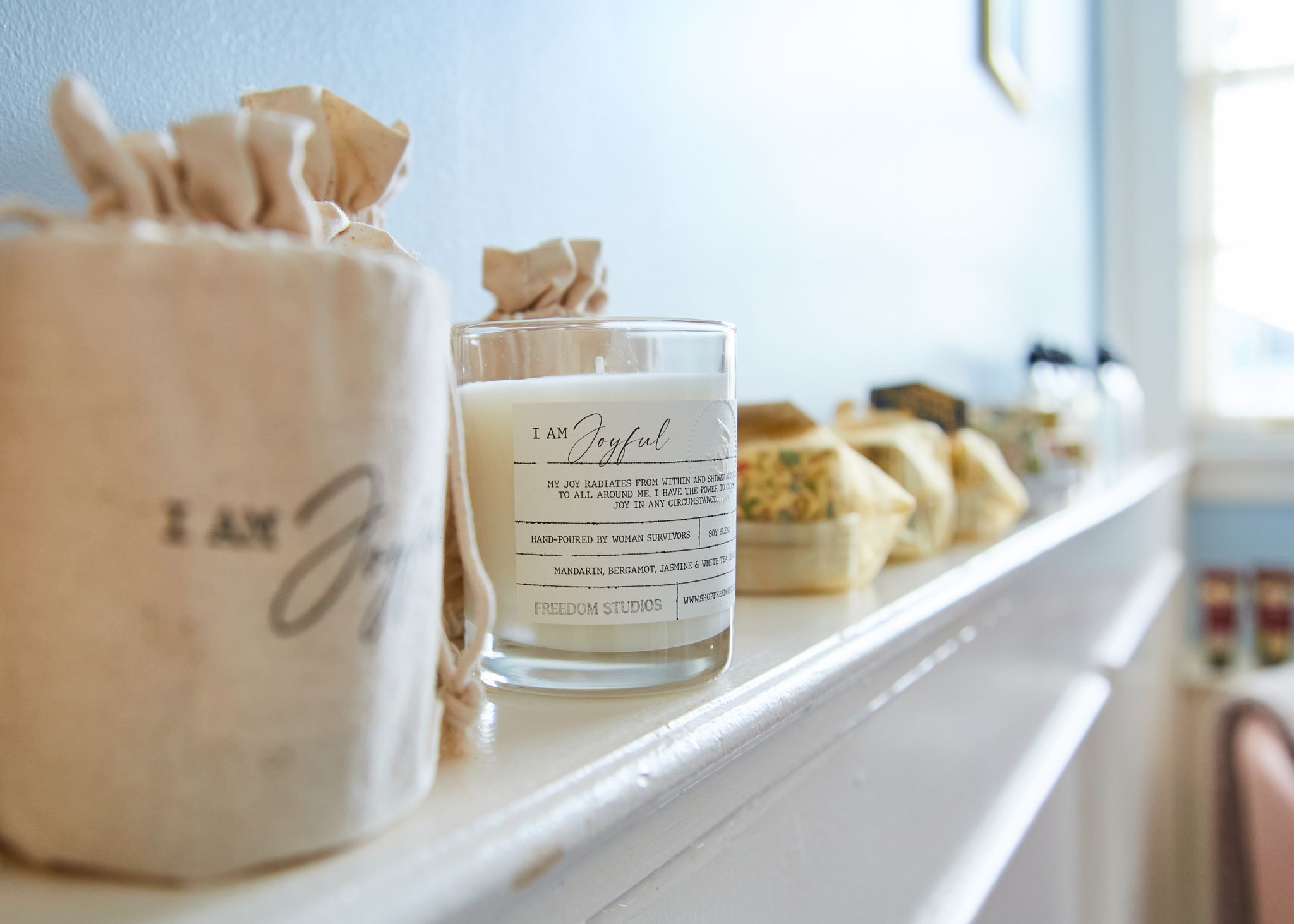 A candle that says "joy" sits on a ledge of the home decor shop.
