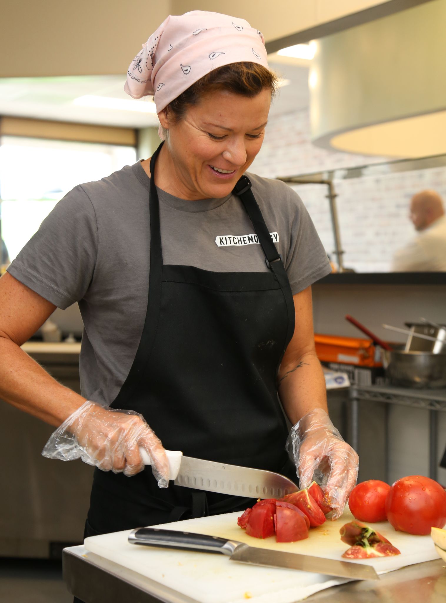 A Kitchenology staff member chops tomatoes at High Point non-profit.