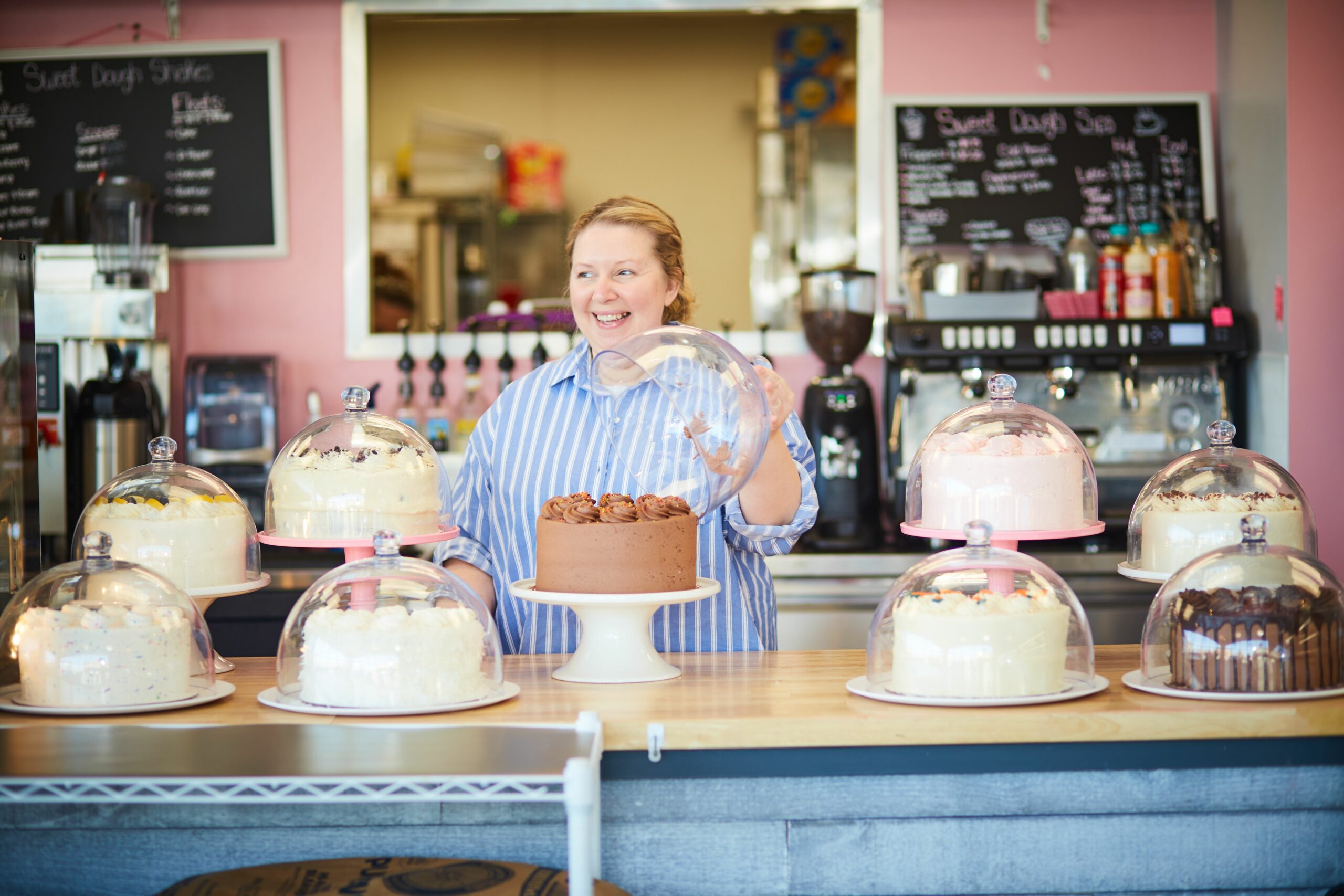 Traci Thompson, owner of Sweet Dough Bake Shop, opens a cake stand in her bakery.