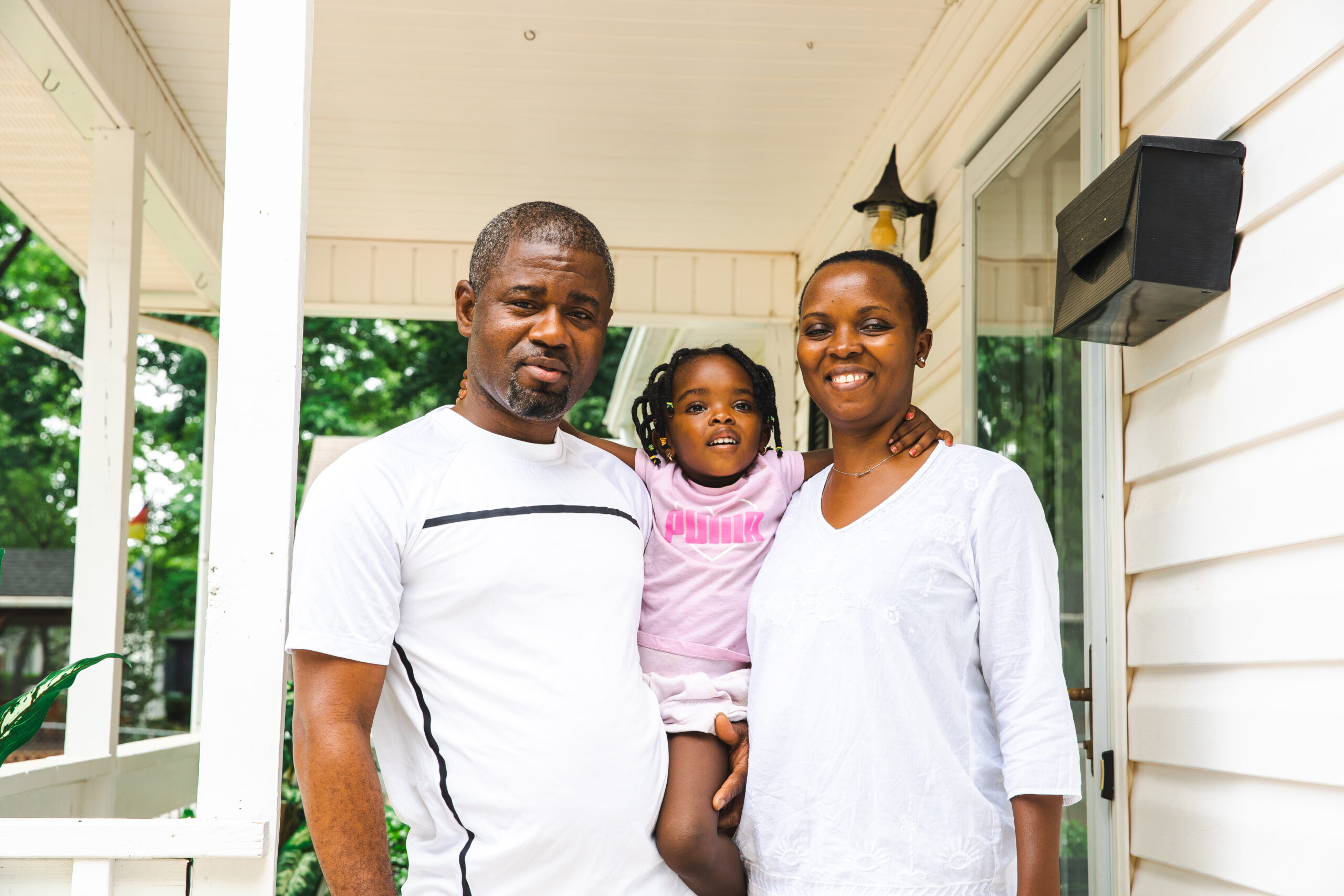Ramazani and Didi Lwamba stand on their front porch in High Point, NC with their daughter.