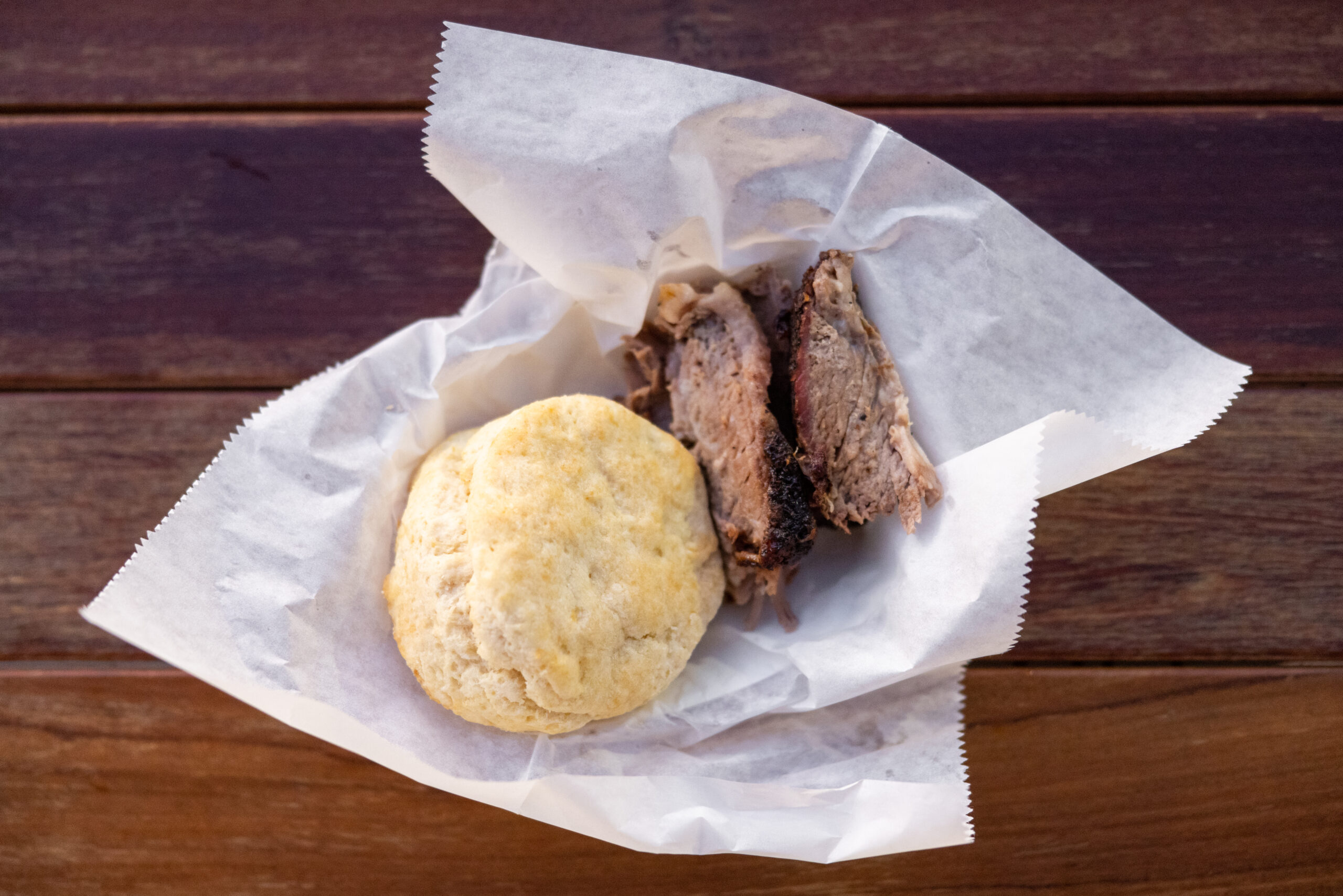 A plate of brisket and a biscuit sits on a picnic table at Stock+Grain Assembly, High Point's food hall.