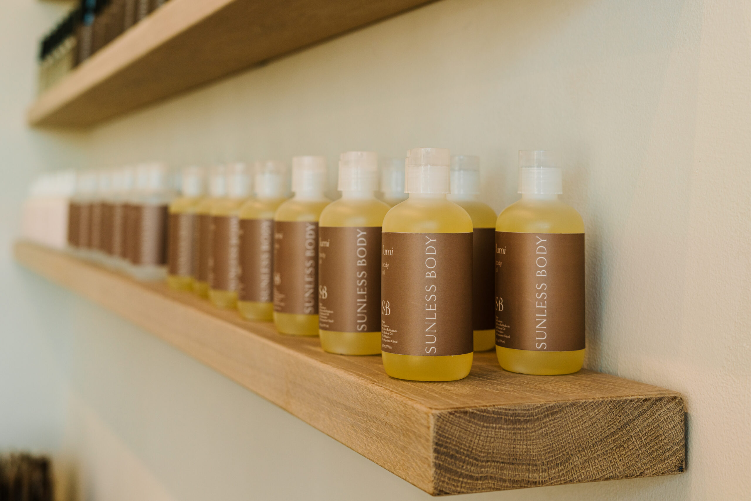Bottles of skincare sit on a shelf at Sunless Body Custom Spray Tanning.