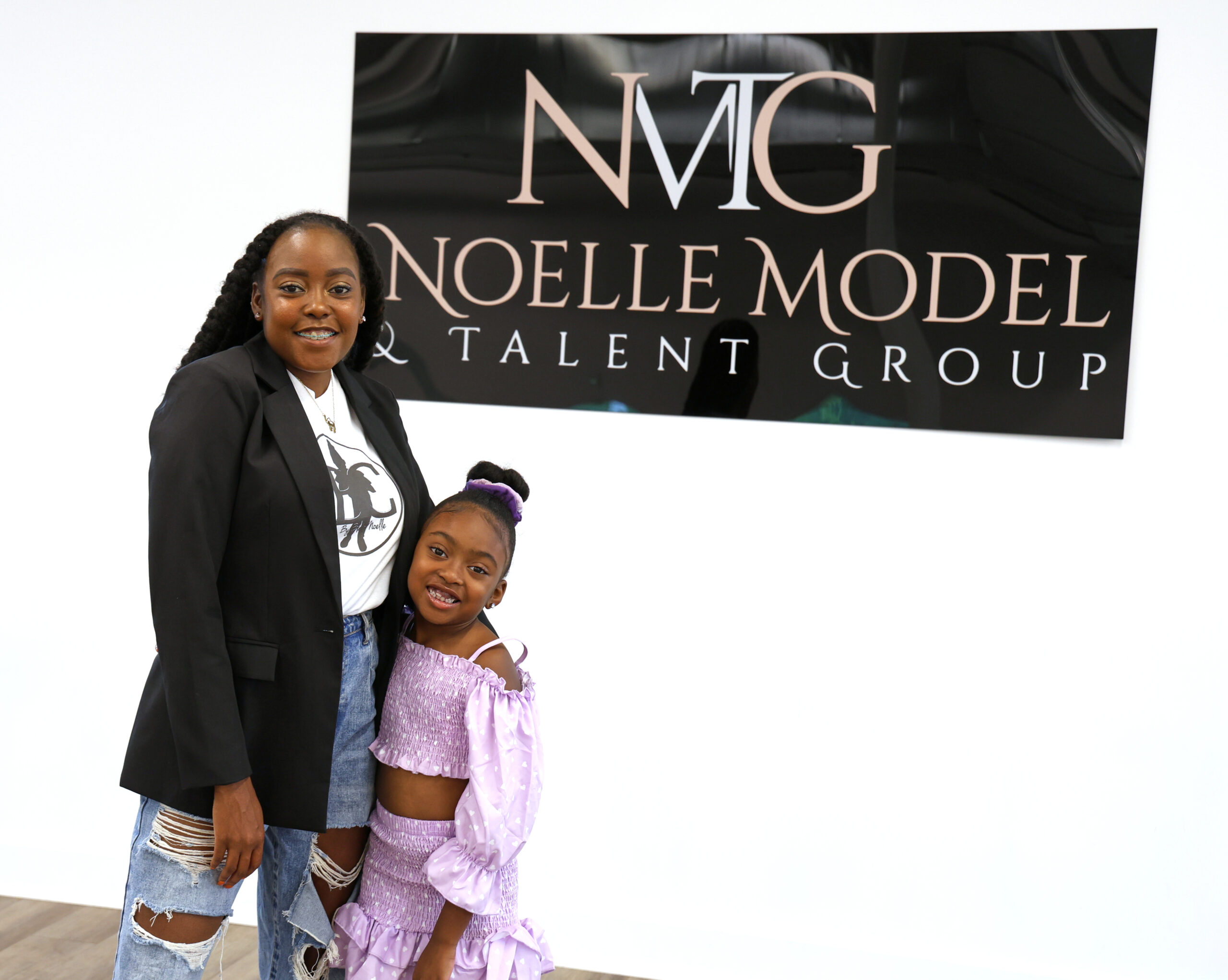 Dr. Cryshaunda Rorie and her daughter, Blair stand in front of a Noelle Model Talent Group sign in High Point, NC.