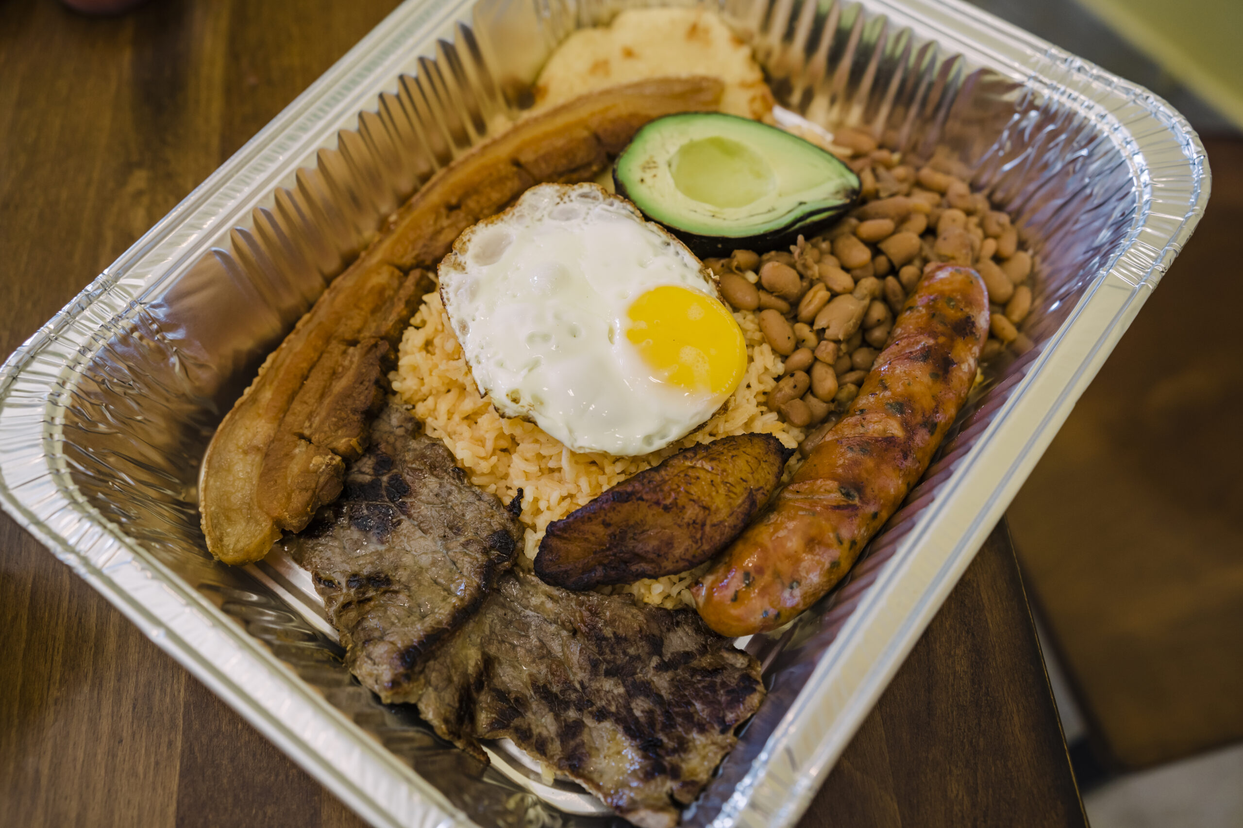 Bandeja Paisa, a traditional Colombian dish that includes: grilled steak, chicharrón, Colombian chorizo, a cheese arepa, fried plantains, rice, beans, egg and avocado.