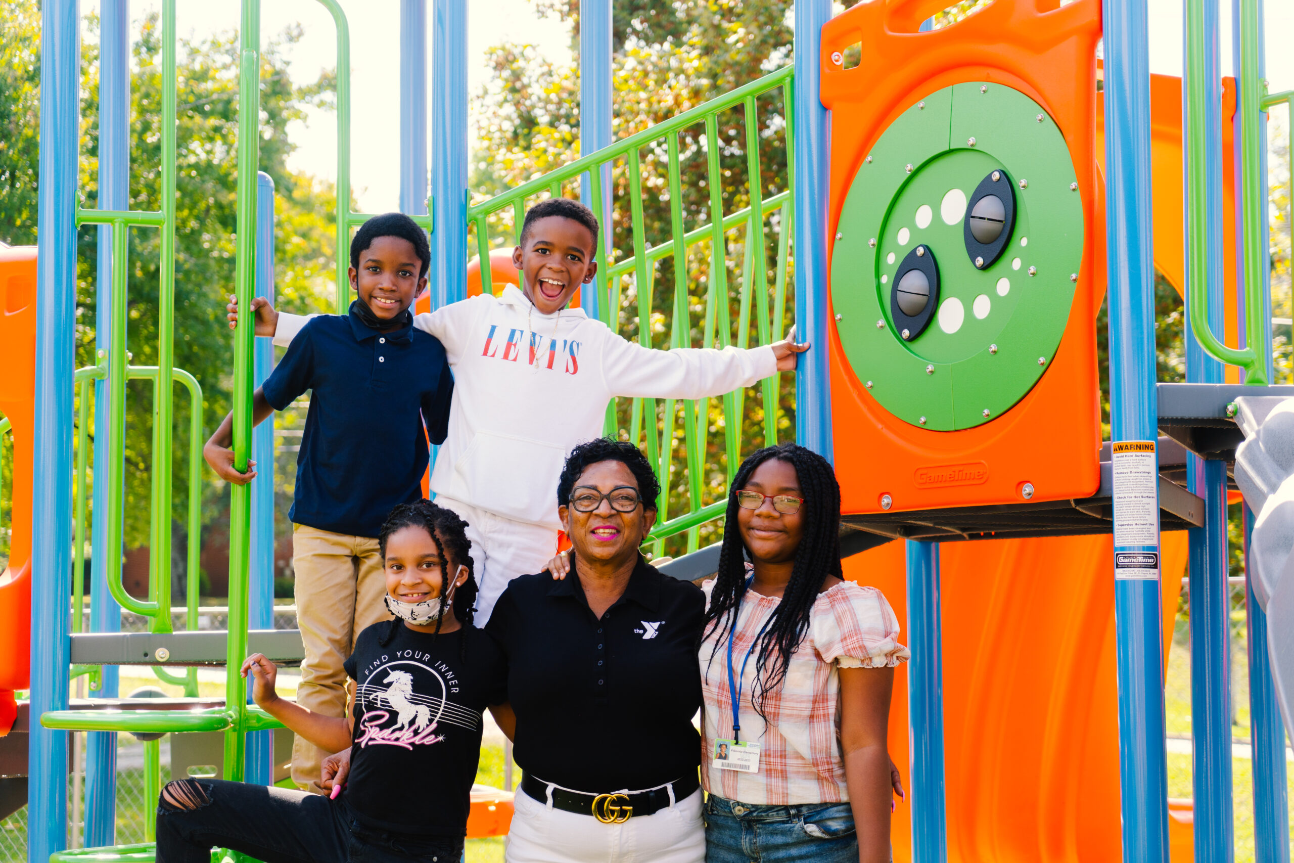 Students stand with Carlvena Foster at the Carl Chavis YMCA on the playground.
